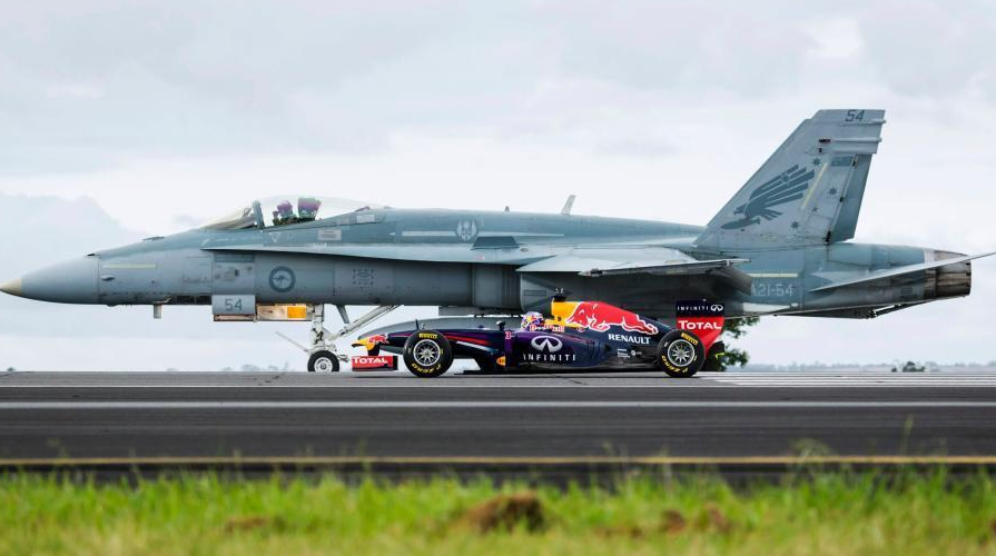 开着方程式赛车与空军一架f/a-18大黄蜂战机在机场跑道进行速度大比拼